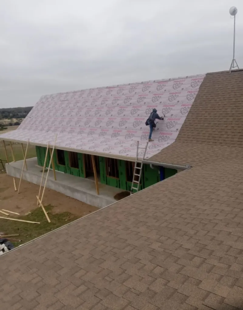 Worker preparing underlayment for a metal roof installation in Topsham